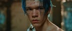 A young man with wet blue hair and a cut on his forehead looks warily to one side.
