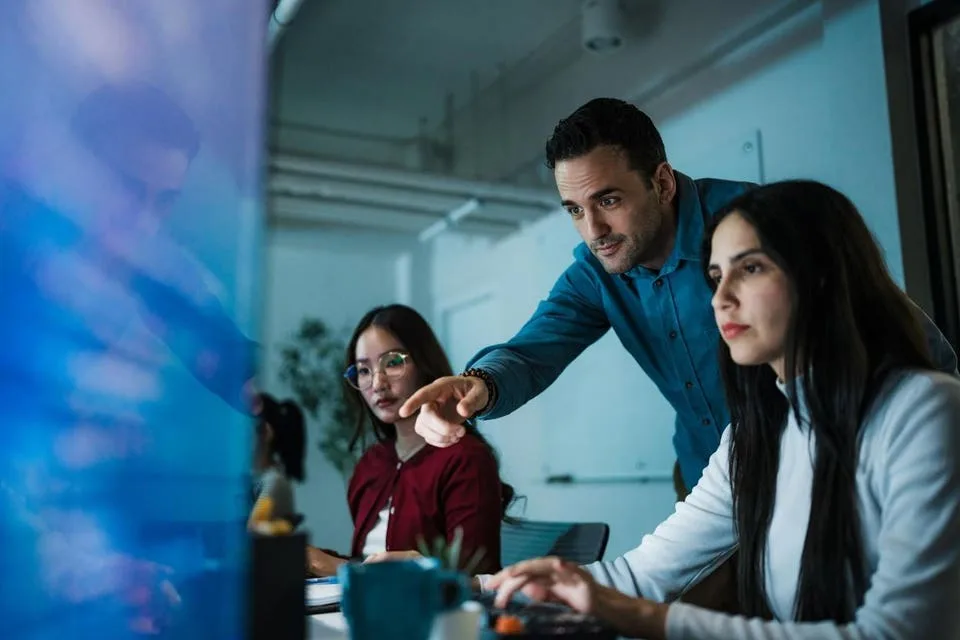 Caucasian male team leader guiding diverse software developers at computer