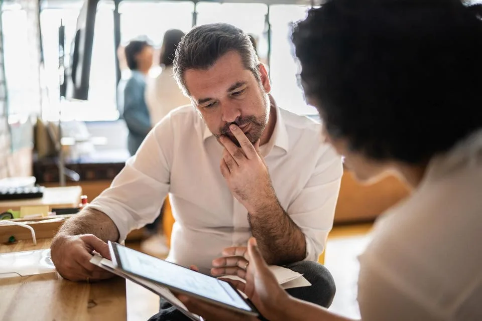 نگاه دو همکار به نمایشگر تبلت در محیط کار
